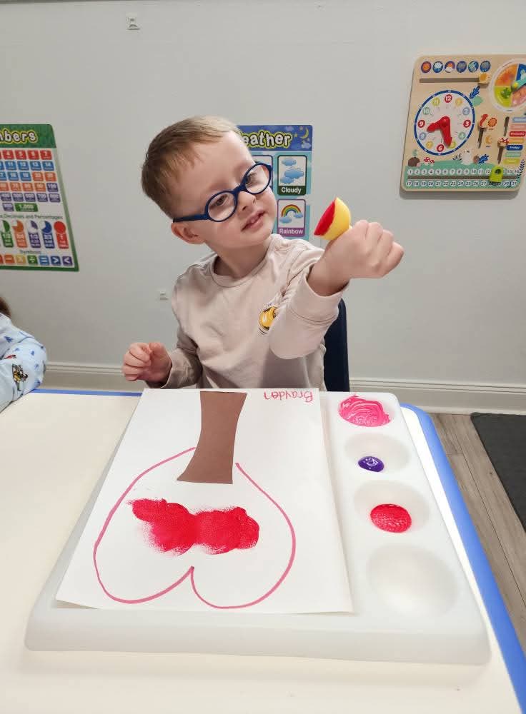 Child proudly showing off a handmade heart craft