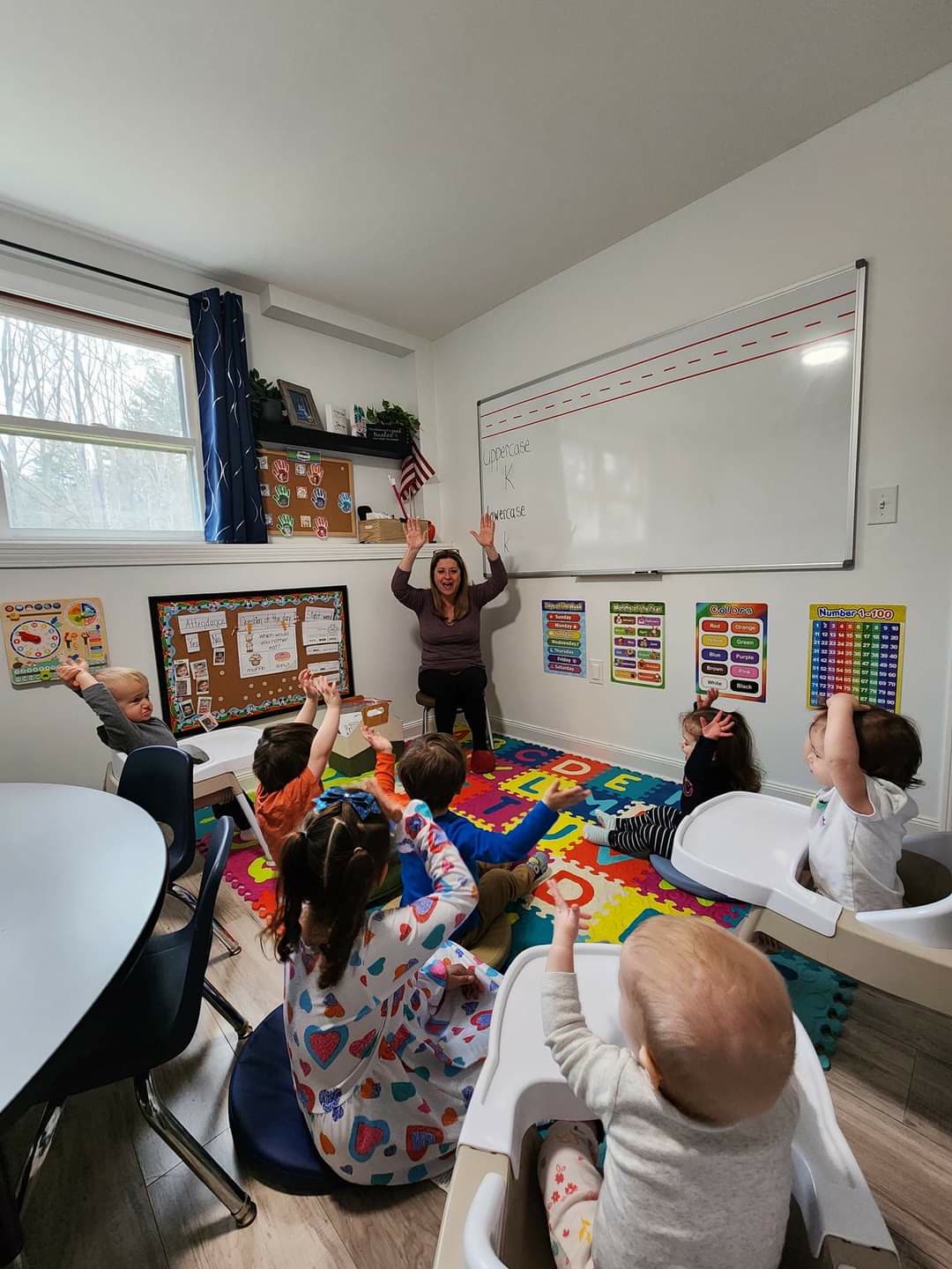 Renee leading circle time with the children on the classroom rug