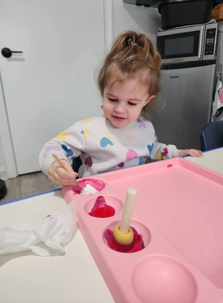 Toddler happily sponge-painting a craft at the table