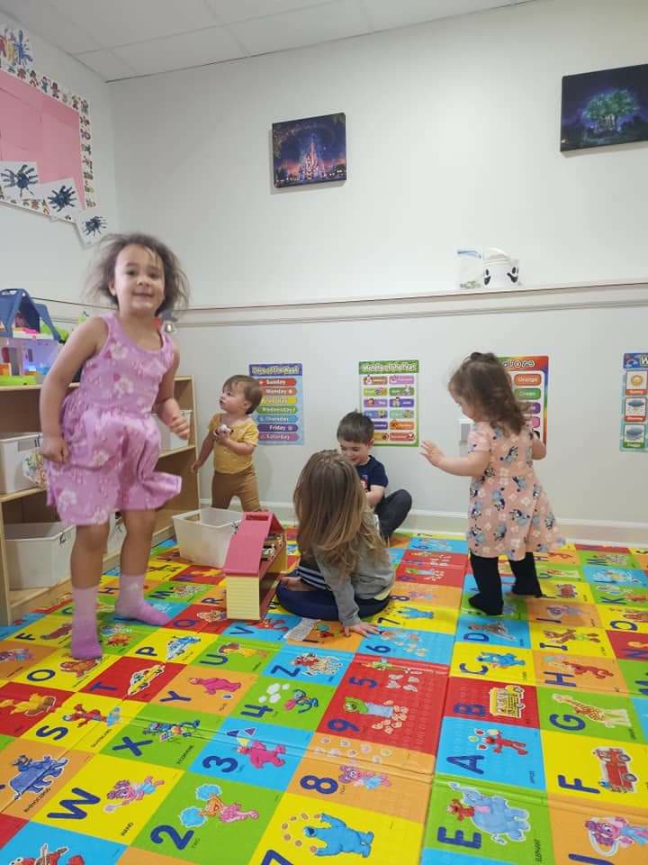 Children dancing and playing together on the alphabet floor mat