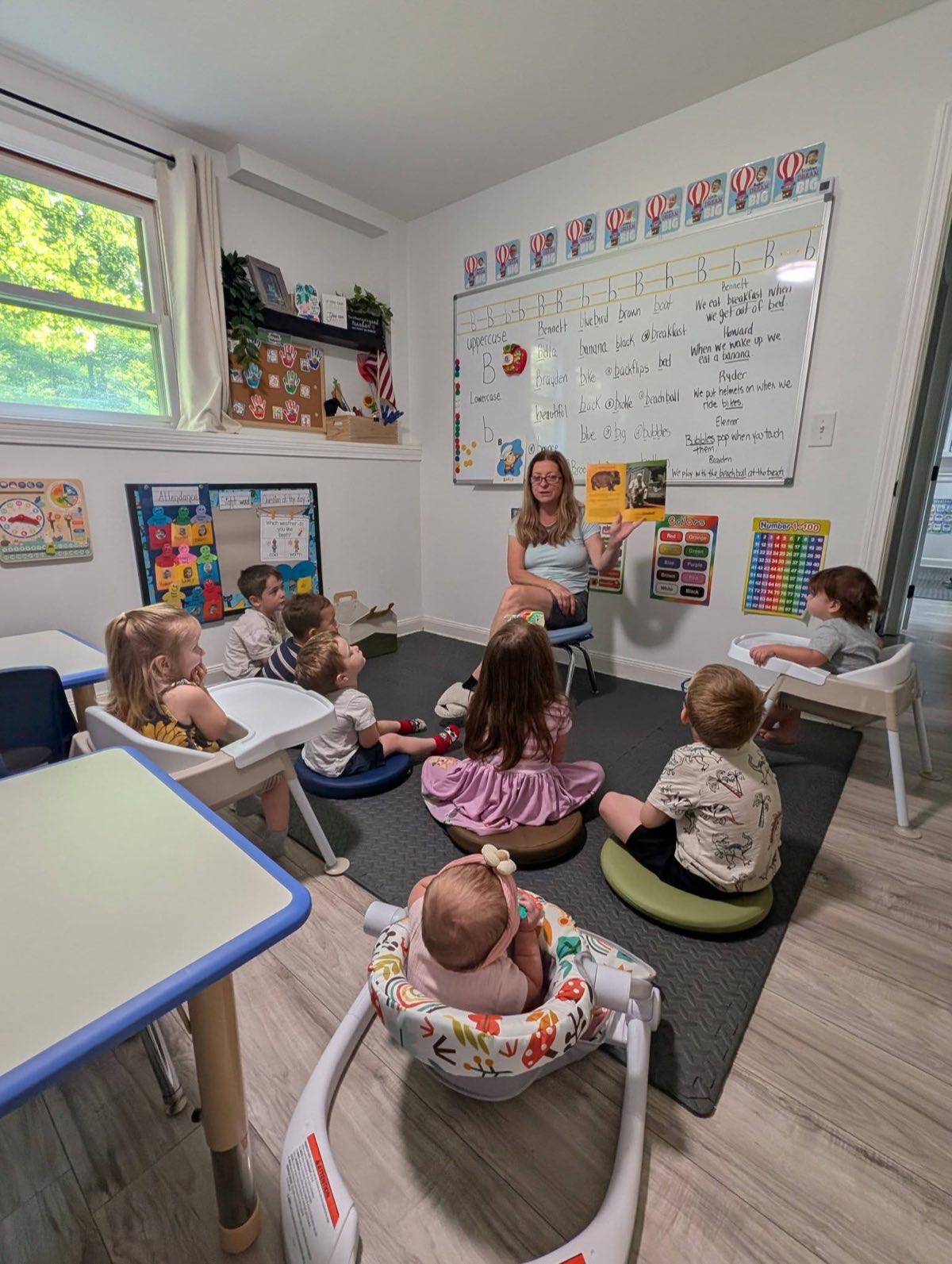 Renee reading a story to a group of children gathered for circle time in the classroom